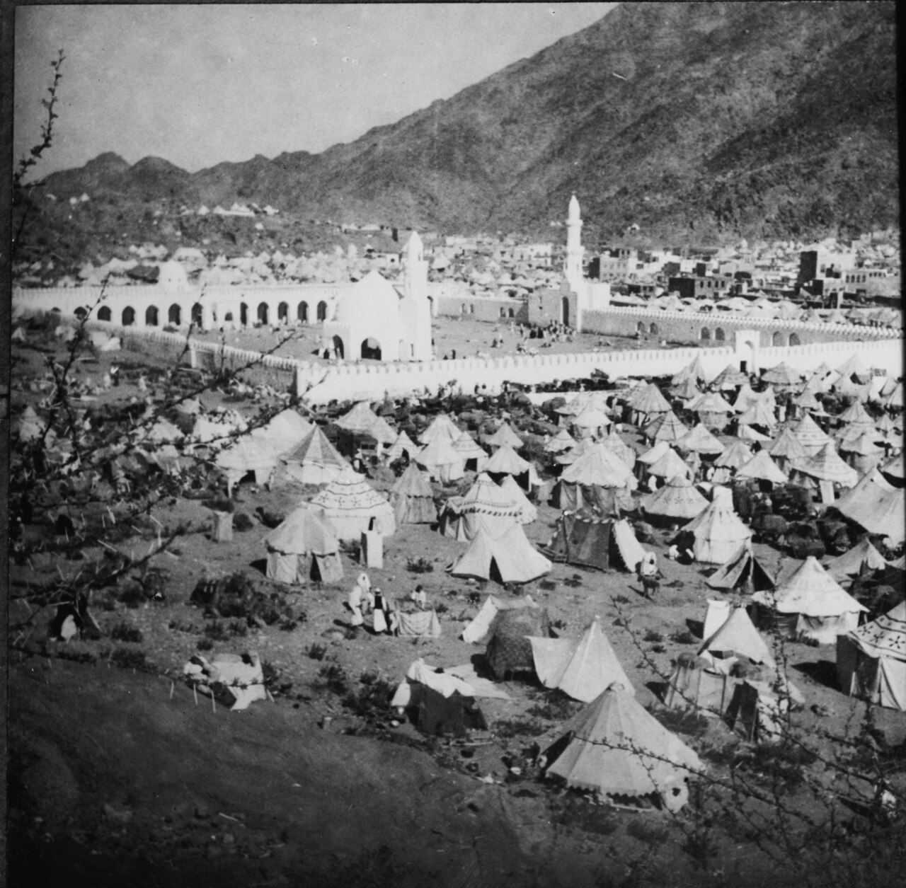 Foto lama kota tenda jemaah haji di luar Makkah dengan pegunungan di belakangnya, sekitar 1910
