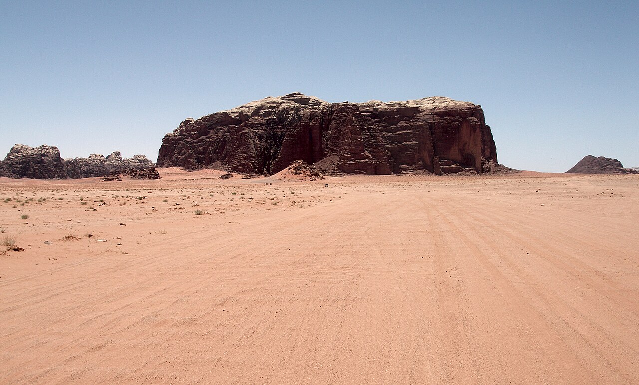 Lembah gurun berpasir merah dengan tebing batu besar di Wadi Rum, Yordania